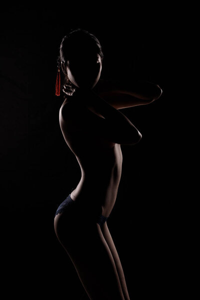 Portrait Swim wear of 20s Asian Woman in shadow low light key with back backlit, side rear view of female turn twist body for healthy shape fashion style. black background smoke exposure