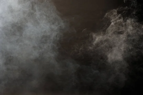 黒い背景に白い煙と霧の濃いふわふわのパフ 抽象的な煙雲 動きが焦点からぼんやりとした 機械からの喫煙の打撃ドライアイスフライと空気中でなびく 効果的なテクスチャ — ストック写真