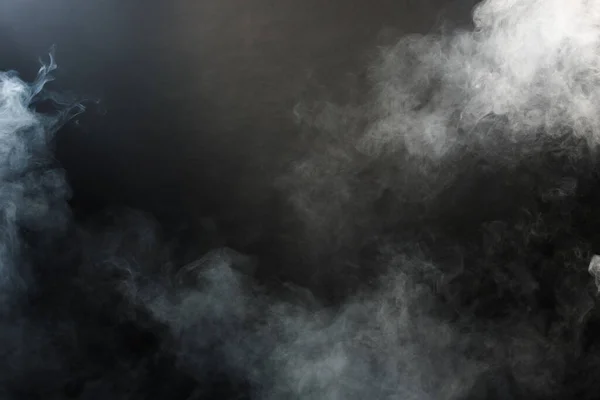 Dense Fluffy Puffs of White Smoke and Fog on Black Background, Abstract Smoke Clouds, Movement Blurred out of focus. Smoking blows from machine dry ice fly and fluttering in Air, effect texture