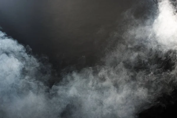 Dense Fluffy Puffs of White Smoke and Fog on Black Background, Abstract Smoke Clouds, Movement Blurred out of focus. Smoking blows from machine dry ice fly and fluttering in Air, effect texture