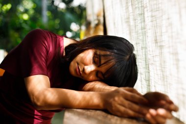 Genç Hintli kadın portresi hala uykulu ve uzanıyor masa gevşeme ortamı, bronzlaşmış tenli Asyalı kadın mor elbise sıcak ve sakin sabah güneşiyle dantel perdenin içinden