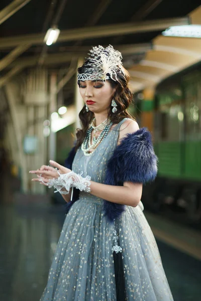 复古时期美丽的盖茨比女人的肖像站在旁边环顾四周 等待着火车的到来 感受着在公共火车站面对浪漫的20年代时尚风格 盖茨比的旧式时尚理念 — 图库照片