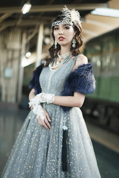 复古时期美丽的盖茨比女人的肖像站在旁边环顾四周 等待着火车的到来 感受着在公共火车站面对浪漫的20年代时尚风格 盖茨比的旧式时尚理念 — 图库照片