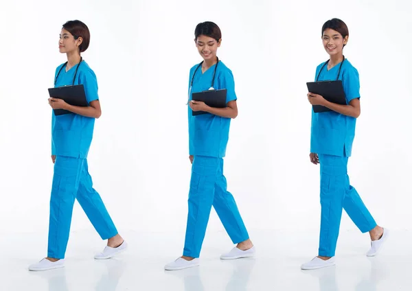 아시아 간호사가 청진기를 착용하고 파란색 유니폼을 왼쪽으로 걸어간다 차트를 가지고 — 스톡 사진