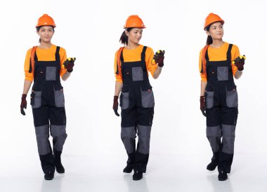 20 'li yaşlarda, Asyalı kadın müteahhit, sol önde yürüyen, güvenlik önlüğü takıyor. Gülümseyen Endüstriyel kadın elektrik sayacı kablosunu beyaz arka planda izole halde tutuyor