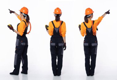 20 'li yaşlarda genç Asyalı kadın müteahhit elektrikçi, parmağıyla havayı işaret ediyor, üniformalı güvenlik kıyafeti giyiyor. Gülümseyen Endüstriyel kadın elektrik sayacı kablosunu beyaz arka planda izole halde tutuyor