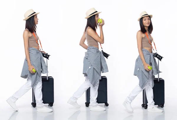 Full length 20s young Asian Woman guide tour traveller, walking forward left right, wear tropical dress pants shoes. Smile tourist female carry camera luggage over white background isolated