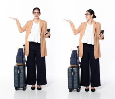 30 'lu yaşlarda, Asyalı, hamile bir kadın iş gezisinde, avuç içi boş, spor ceket giyen, resmi ayakkabılar giyiyor. Gülümseyen ofis kadını sırt çantasındaki telefonu beyaz arka planda tek başına taşıyor.