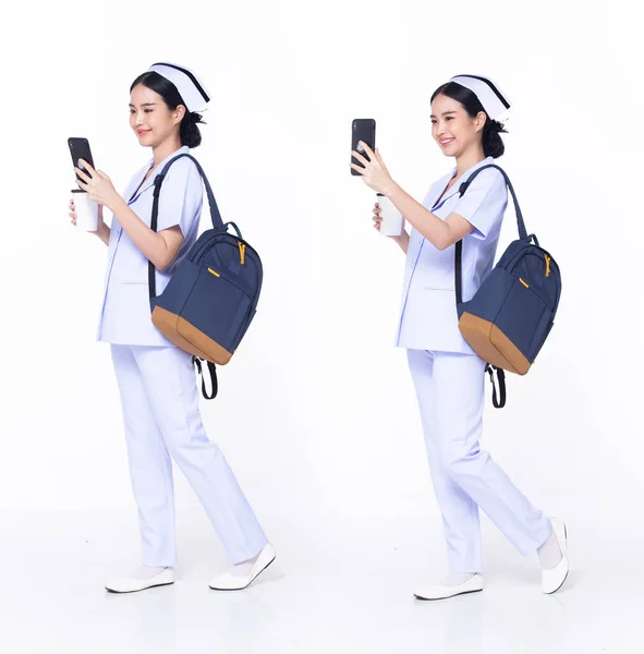 Full length 30s 20s Asian Woman Nurse hospital, walking forward left right, wear formal uniform pant shoe. Smile Hospital female carry backpack coffee cup internet phone over white background isolated