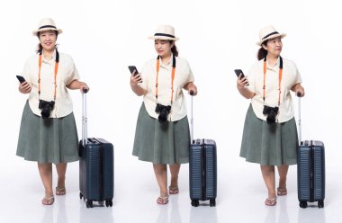 40 'lı yaşlarda, Asya' lı 50 'li yaşlarda, tatil turisti, sağdan sola doğru yürüyor, tropikal terlik giyiyor. Gülümse bayram kadını, harita taşı, internet telefonu bagajını beyaz arka planda izole et.