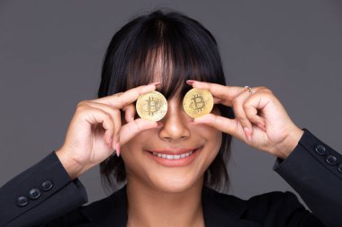 Asian Indian business woman show beautiful smile happy lips, show BTC bitcoin cryptocurrency. India trader Female express feeling wellbeing digital future money in studio over gray background isolated