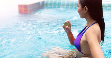 Tanınmayan bir kadının elinde BTC bitcoin kripto para, güçlü güneşin altında yüzme havuzunda güzel bir kız. Bronz tenli kadın ticareti dijital para değişimi tatilin her yerinde, kopyalama alanı