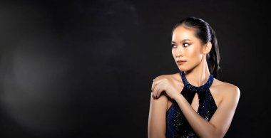 Half body of Asian beautiful woman wear blue evening sequin gown, fashion vintage poses. Young female stand express feeling happy smile strong over black background isolated copy space
