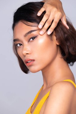 Beautiful Tanned skin woman wear yellow dress open shoulder with clean look make up and curl hair. Portrait young girl in attractive natural fashion face express feel smile, isolated gray background