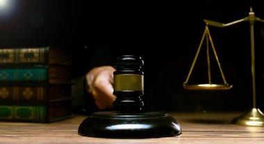 Justice Hammer and law concept. Judge in dark courtroom with the gavel brass scale text book hold hammer to make fair legal work on criminal guilty as professional authority judicial decision