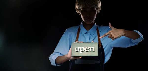 Caucasian person hold Open Sign Business to show service at door entrance store, cafe, retail and welcome shop. Happy Entrepreneur female blonde hair wear waitress dress as open business time concept
