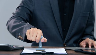 Person Signing Approval document, certificate, legal agreement in office by pen and stamp hand. Authority apply law to do contract paperwork form by public notary clerk or official lawyer, copy space