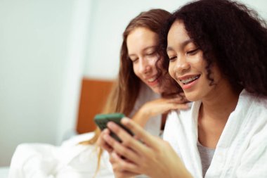 Caucasian and black women love together and hug hold as diversity person. Young Adult Romantic couple look at smart phone photo chat text as feeling happy smile togetherness and diversity, copy space