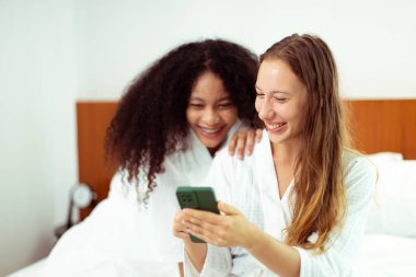 Caucasian and black women love together and hug hold as diversity person. Young Adult Romantic couple look at smart phone photo chat text as feeling happy smile togetherness and diversity, copy space