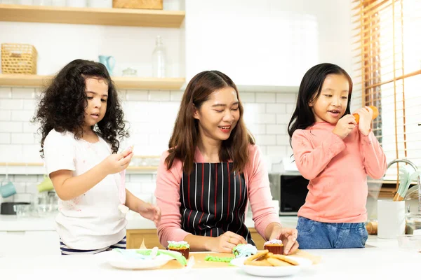 Group of Diverse Family, Asian and Arab Preschool African Arab kid person make Cake cooking in kitchen, Mother prepare decoration pretty with fun educate on snack. Cream mess all over face, copy space