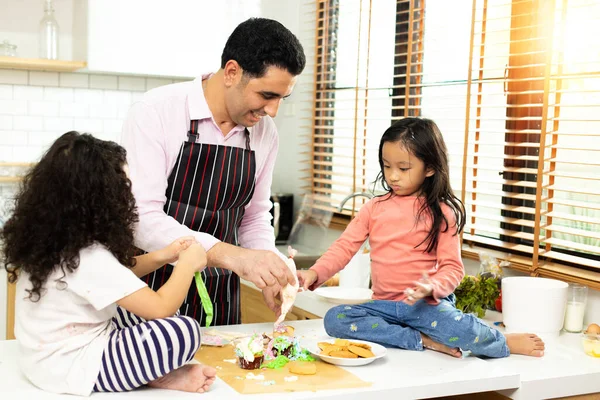 Group of four Diverse Family, Asian and Arab Preschool African Arab kid person make Cake cooking in kitchen, Father Mother prepare decoration pretty with fun educate. Cream mess over face, copy space