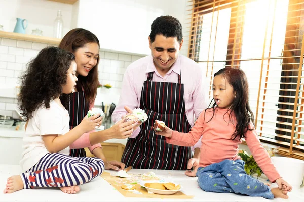 Group of four Diverse Family, Asian and Arab Preschool African Arab kid person make Cake cooking in kitchen, Father Mother prepare decoration pretty with fun educate. Cream mess over face, copy space