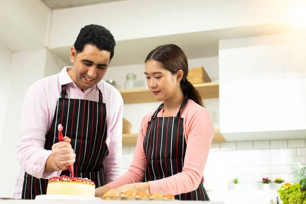 Asian woman and Arab man as Young adult couple learn how to bakery cooking cake online course kitchen. Diverse Family video to cyberspace class on laptop as blogger social media together, copy space
