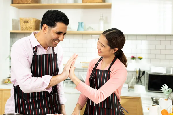 Asian woman and Arab man as Young adult couple learn how to bakery cooking cake online course kitchen. Diverse Family video to cyberspace class on laptop as blogger social media together, copy space