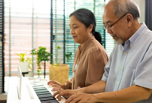 Elderly senior couple play Piano music together. Group of Two Asian smart mature Person retire and get pension fund. Grandparent express feeling happy treatment. Concept grow old together, copy space