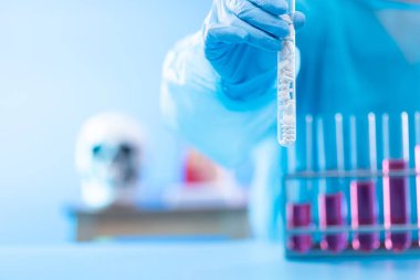 Laboratuar asistanı üniforması ve maske eldivenleriyle deney tüpü ve bilim laboratuvarı araştırma numunesi tutarken, grafik büyüme geliri olarak biyoloji kimyasalı üzerindeki gelişmeyi analiz ederken yatırım gelirini artırıyor, yer kopyalıyor.