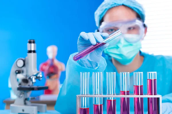 Lab assistant uniform with mask gloves holding test tube with science laboratory research sample while analyzing development on biology chemical as graph growth increase investment revenue, copy space