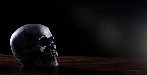 黒い背景の上に古い木製のテーブルの上にハロウィーンの人間の頭蓋骨 恐怖悪歯恐怖と怖い コピースペースを示すハロウィーンの祭りで頭のための頭蓋骨の骨の骨の形 — ストック写真