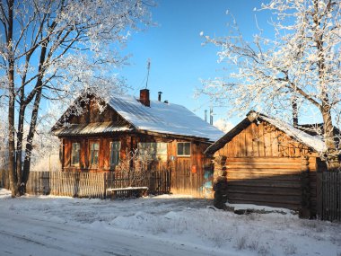 Soğuk bir kış sabahı. Eski bir ev, küçük bir Rus kasabasının sokağı. Rus ahşap geleneksel evi. Ağaç donuyla kaplı. Kış. Rusya, Ural, Perm bölgesi. Elovo.