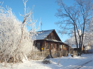 Soğuk bir kış sabahı. Eski bir ev, küçük bir Rus kasabasının sokağı. Rus ahşap geleneksel evi. Ağaç donuyla kaplı. Kış. Rusya, Ural, Perm bölgesi. Elovo.