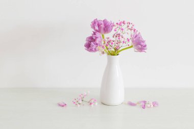 Beyaz arka planda pembe laleler ve çingeneler.