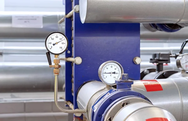 Pressure gauge and thermometer on a pipeline in a gas boiler room.