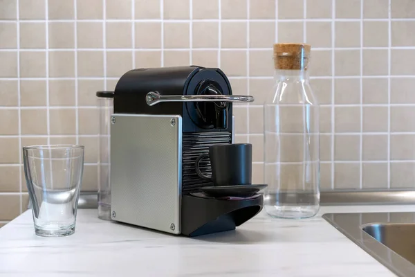 Capsule coffee machine with black coffee cup on the kitchen table.