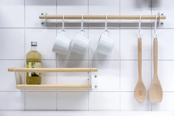 Kancalarda beyaz bardaklar, tahta kaşıklar ve içkiyle dolu raflar. Mutfak eşyaları..