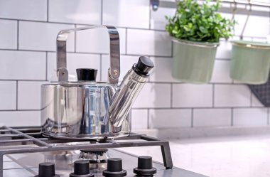 Mutfak ocağında ıslık çalan metal çaydanlık..