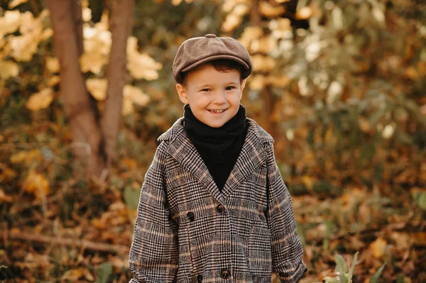 Un enfant heureux dans un manteau d'automne marche dans un parc jaune d'automne. — Photo