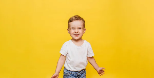 Retrato de um menino rindo bonito em um fundo amarelo. Espaço de cópia. — Fotografia de Stock