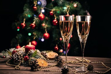 Noel arkaplanda şampanya bardakları süslenmiş bir Noel ağacı ve bir çelenk.