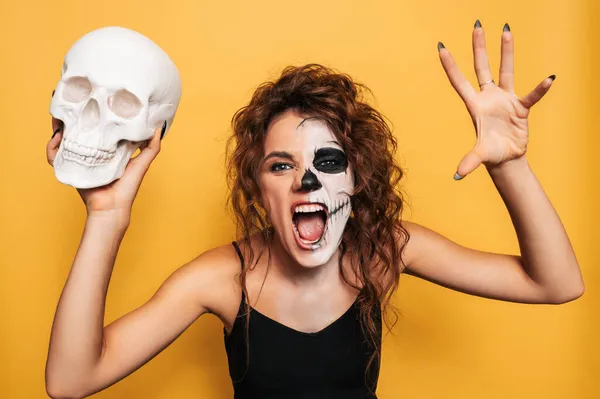 Estúdio tiro de uma menina em um traje de espíritos malignos em uma festa de fantasia de Halloween com um crânio em suas mãos. A arte do Halloween — Fotografia de Stock