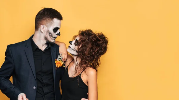 Celebração de Halloween. Um estúdio filmado de um jovem casal em trajes festivos de Halloween e com maquiagem no rosto. Um lugar para o seu texto, publicidade. — Fotografia de Stock