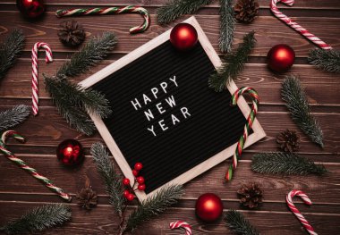 Yeni yıl süslemeleri, köknar dalları, kozalaklar, toplar ve karamel kamışlarla dolu bir mektup panosuna yeni yılınız kutlu olsun. Üst Manzara. Noel kartı..