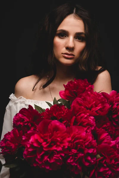 赤牡丹の花束を手にした美しく官能的な若い女性の肖像画 — ストック写真