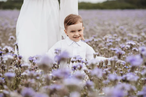Glad leende pojke löper genom ett blommande fält — Stockfoto