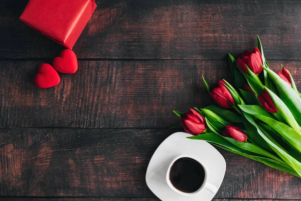 Μπουκέτο κόκκινες τουλίπες σε ξύλινο φόντο με ένα φλιτζάνι καφέ. Ανοιξιάτικα λουλούδια Φόντο ημέρας μητέρων. — Φωτογραφία Αρχείου