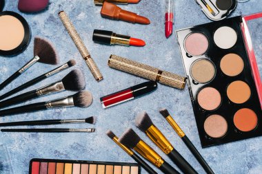 Makyaj fırçaları, dekoratif kozmetik ürünleri, mavi arka planda takma kirpikler. Yukarıdan görünüm