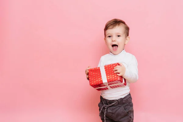 Gift in Hands Boy. Happy Baby Boy with Gift Box in Hands isolated on pink background. — Fotografia de Stock